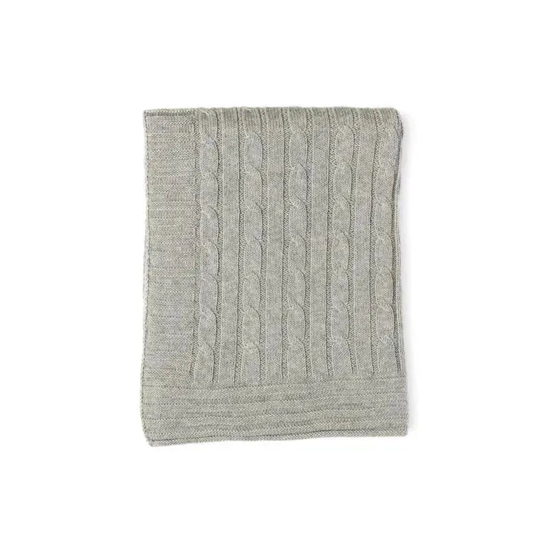 Grey cable knit blanket folded neatly, featuring a textured pattern of cables running vertically.
