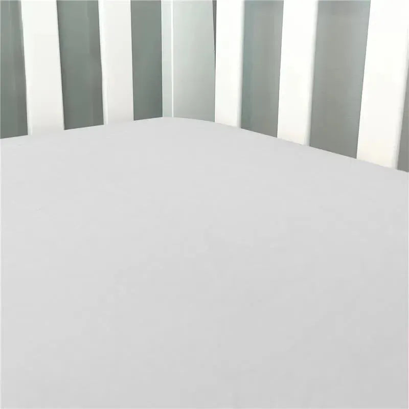 Solid grey flannel crib sheet fitted snugly on a crib mattress, surrounded by white crib slats.