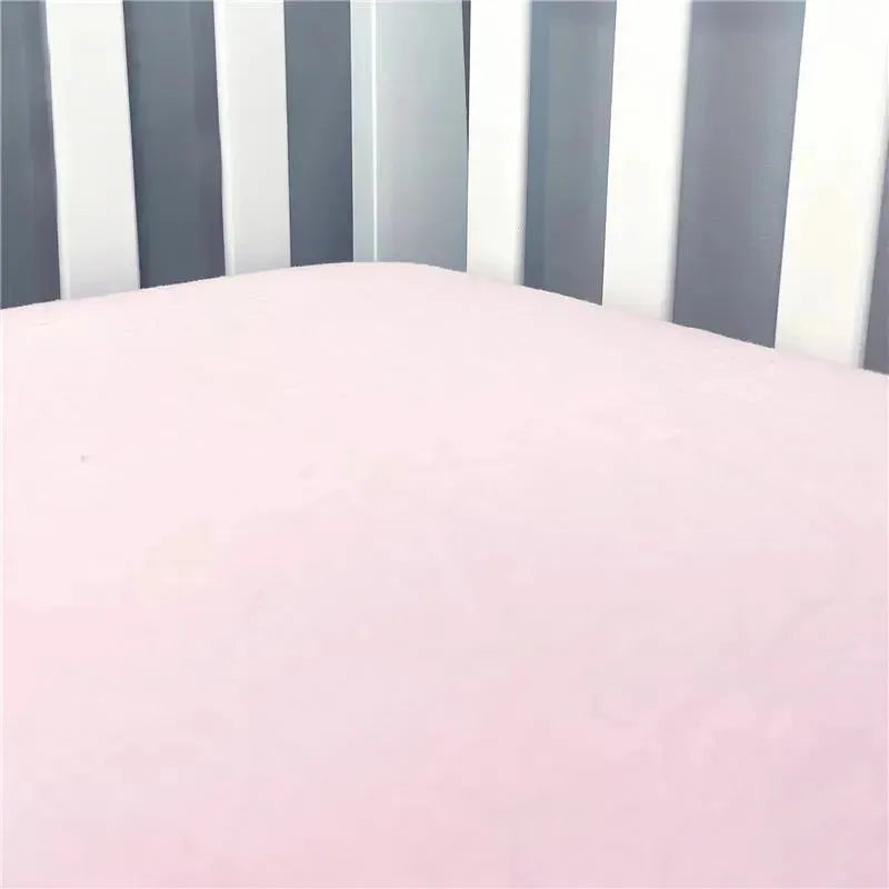 Solid pink flannel crib sheet displayed on a crib mattress, surrounded by light-colored wooden slats.