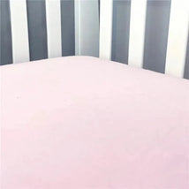 Solid pink flannel crib sheet displayed on a crib mattress, surrounded by light-colored wooden slats.