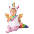 Toddler wearing a fluffy white unicorn costume with rainbow mane and golden wings, smiling while sitting.