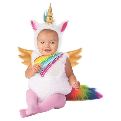 Toddler wearing a fluffy white unicorn costume with rainbow mane and golden wings, smiling while sitting.