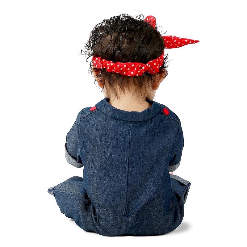 Toddler wearing a denim jumpsuit with red button details and a red polka dot headband, styled as Rosie the Riveter.