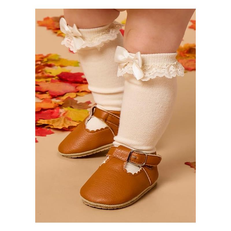 Knee-high socks in ivory with lace ruffle and bow, worn with brown leather shoes, on a child among colorful autumn leaves.