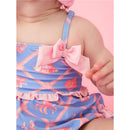 Baby girl in a tropical-themed one-piece swimsuit featuring a pink bow and ruffled trim, surrounded by seashell and crab prints.