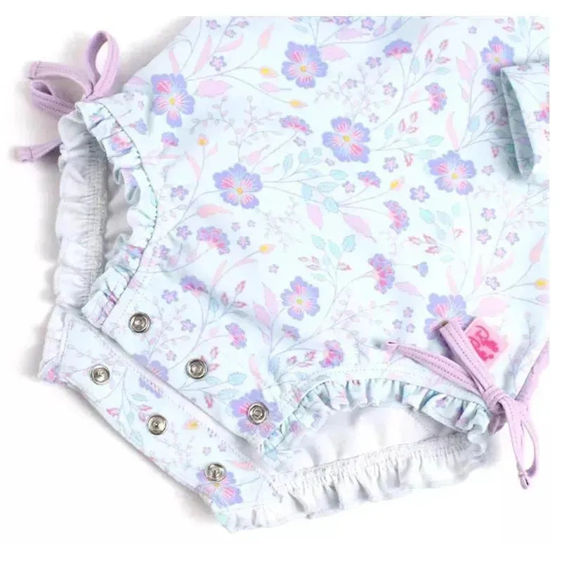 Long sleeve one-piece rash guard featuring a pastel floral design with ruffle details and snap closures.