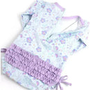 Long sleeve one-piece rash guard by Rufflebutts featuring a floral pattern in pastel colors and ruffled lavender accents.