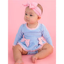 Periwinkle blue seersucker long sleeve one-piece swimsuit with pink bows, worn by a baby sitting against a pink background.