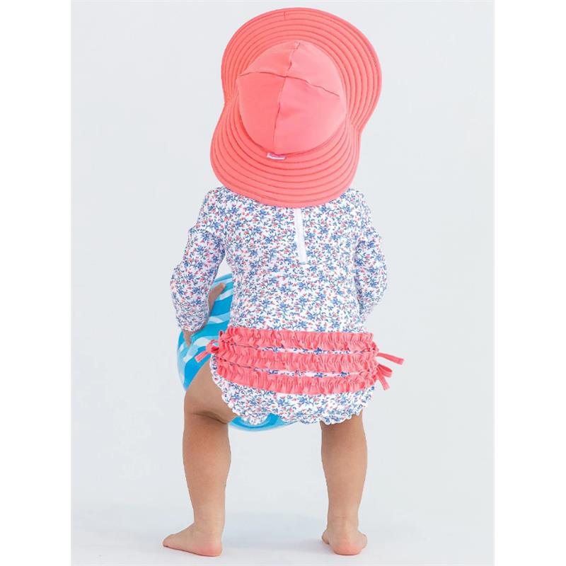 Kids swim hat in bubblegum pink worn by a child, who is facing away, with a floral long-sleeve swimsuit and holding a beach ball.