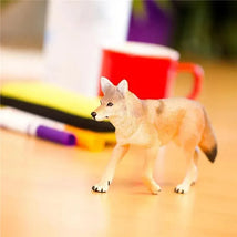 Coyote toy figurine standing on a desk, detailed with realistic colors and features, surrounded by office items.