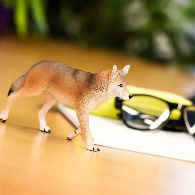 Detailed 6.5-inch Coyote figurine walking on a table, with glasses and notepad nearby.