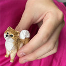 Realistic Pomeranian figurine held in a hand, showcasing intricate detail and texture, including a fluffy tail and expressive face.
