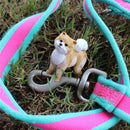 Realistic Pomeranian dog figure on a grassy surface next to a colorful dog leash.