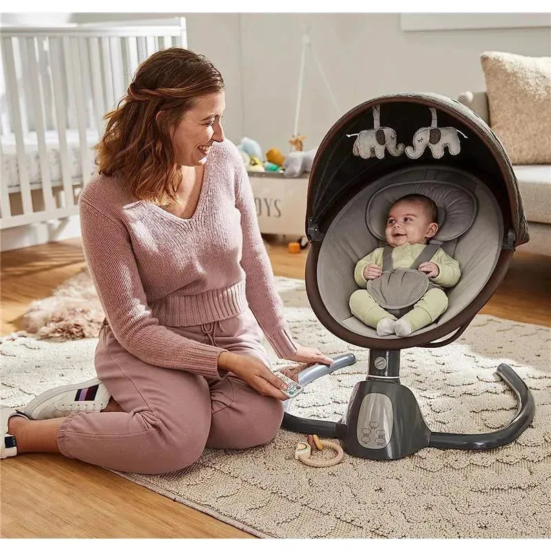 A woman kneels beside a Safety 1st Bluetooth swing, smiling at the baby inside, who wears a green outfit.