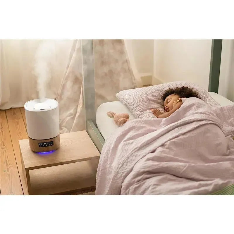 Smart humidifier on a bedside table near a sleeping child, with a soft blanket and a stuffed toy.