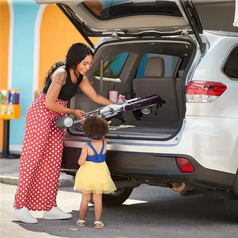 A mother in polka-dot pants is taking out a Safety 1st Disney Baby Character Umbrella Stroller from her SUV as her toddler watches.