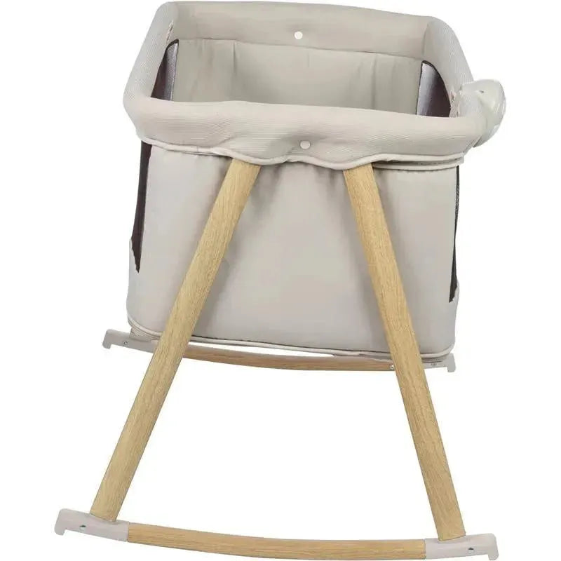 2-in-1 bassinet and play yard with a beige fabric and wooden rocking legs, designed for soothing baby sleep and play.