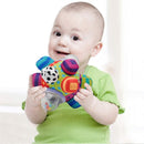 Baby smiling while holding a colorful Sassy Developmental Bumpy Ball, featuring various textures and a clear section with beads.