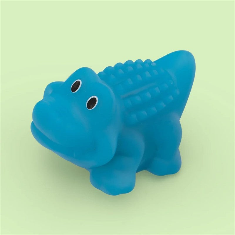 Blue alligator-shaped bath toy with textured back, featuring two black eyes, set against a light green background.