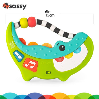 Sassy Rock-A-Dile Musical Toy features a green alligator design with colorful beads, buttons for sound, and a playful smiling face.