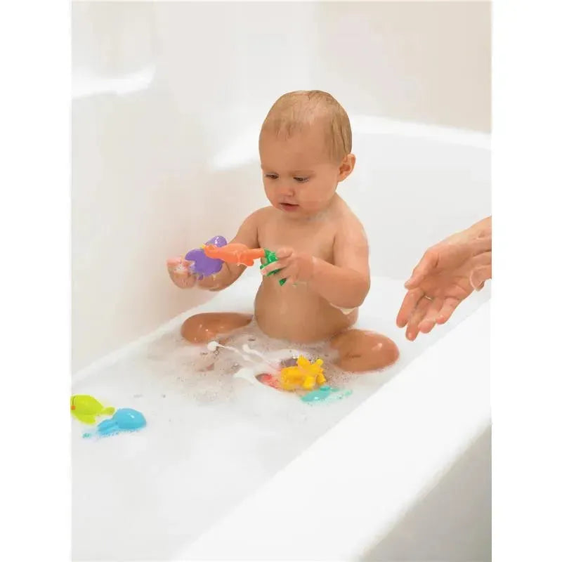 A baby sitting in a bathtub filled with bubbles, playing with colorful sea creature bath toys.