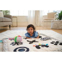 Sassy Wimmer Seek & Explore Mat with baby, colorful toys, and various tactile designs on a soft play surface.
