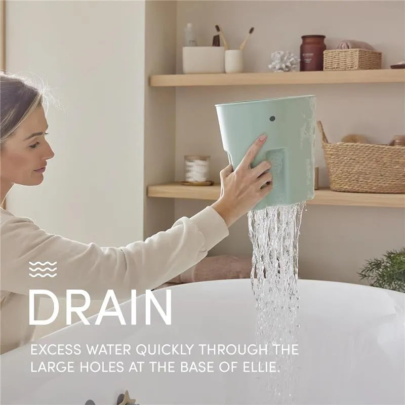 A woman drains water from a grey Shnuggle Ellie bath toy storage scoop, showcasing its large holes at the base.