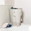 Taupe Shnuggle Ellie Bath Toy Storage Scoop beside the wall, holding bath toys, resembling an elephant.