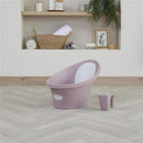 Newborn baby bath by Shnuggle in blossom color, featuring a white interior and a small cup beside it, set in a modern nursery.