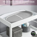 Taupe Shnuggle squishy baby changing pad on a white changing table, designed to fit most standard tables.