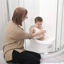 Toddler bath tub in white and grey with a child playing in bubbles, while a caregiver assists beside.