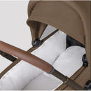 Modular stroller bassinet in Maple color, featuring a brown hood, white interior cushioning, and a sleek handlebar.