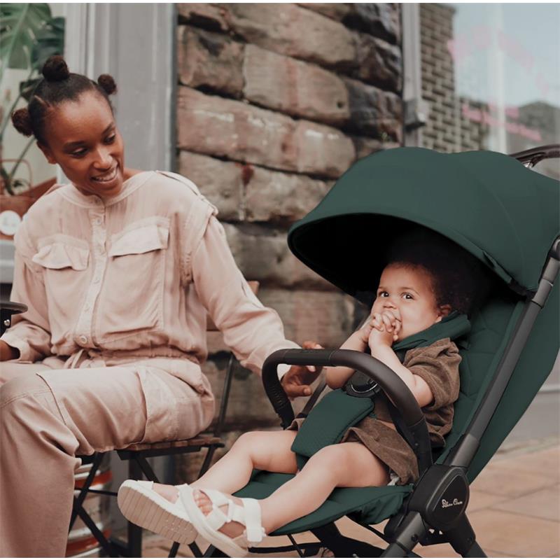 Lightweight Silver Cross Clic stroller in Conifer green with a child sitting comfortably and a smiling adult nearby.