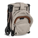 Clic Lightweight Stroller in Latte color, folded with a soft, textured fabric and brown handle, showcasing compact design.