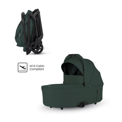 Compact folding bassinet in Conifer color, featuring a dark green fabric and IATA cabin compliance icon.