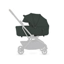 Silver Cross Nia Compact Folding Bassinet in Conifer, featuring a dark green fabric with a removable canopy and zippers.