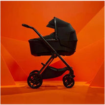 Silver Cross Reef Automobili Lamborghini Arancio stroller and bassinet in black against an orange background.
