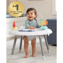 Baby in a gray top playing in a Skip Hop 2-in-1 Activity Center with colored toys and developmental features.
