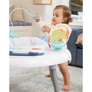 A toddler plays with the Skip Hop 2-in-1 Baby Activity Center, engaging with colorful toys and a textured surrounding.