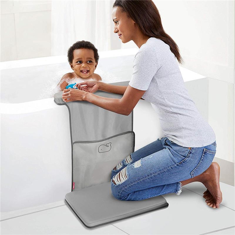 Mother assisting a smiling baby in a bath, using the grey Skip Hop Baby Bath Moby elbow saver and kneeler.