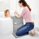 Mother kneeling on a grey Skip Hop Baby Bath Moby Elbow Saver & Kneeler, smiling at her child in the bath while holding a bottle.