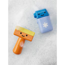 Colorful bath toys, an orange scraper with a smiling face and a blue bottle, resting on soapy water.