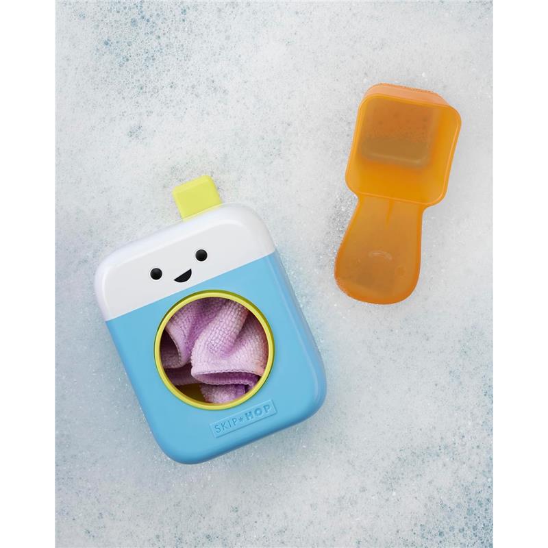Bright blue bath toy shaped like a washing machine, featuring a smiling face, holding a purple washcloth, with an orange scoop nearby.