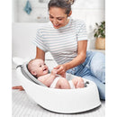 A woman smiles at a happy baby in a white Skip Hop 3-Stage Smart Sling Bath Tub with a gray mesh seat.