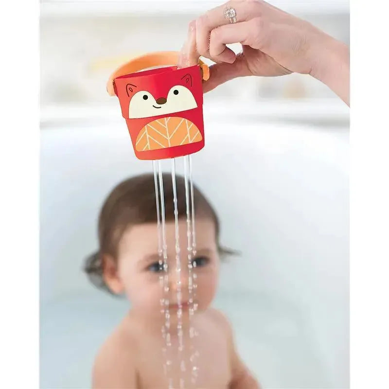 Colorful red and orange fox-shaped bath bucket pouring water onto a child in a bathtub.