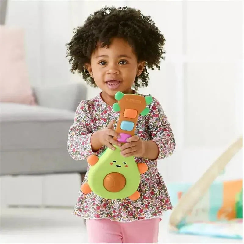 Toddler with curly hair holding a colorful Skip Hop Farmstand Rock-A-Mole Guitar toy, smiling joyfully.