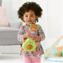 Toddler with curly hair holding a colorful Skip Hop Farmstand Rock-A-Mole Guitar toy, smiling joyfully.