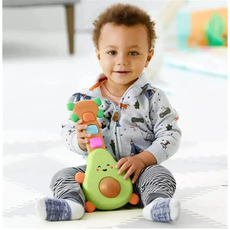 Baby wearing a gray sweater sits on a play mat, holding a colorful Skip Hop Farmstand Rock-A-Mole Guitar toy.