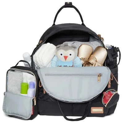 Skip Hop Suite Diaper Bag Backpack Set in black, featuring organized pockets, diapers, an owl toy, and skincare products.