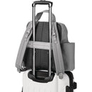 Grey Skip Hop diaper bag backpack is attached to a wheeled suitcase for easy transport.